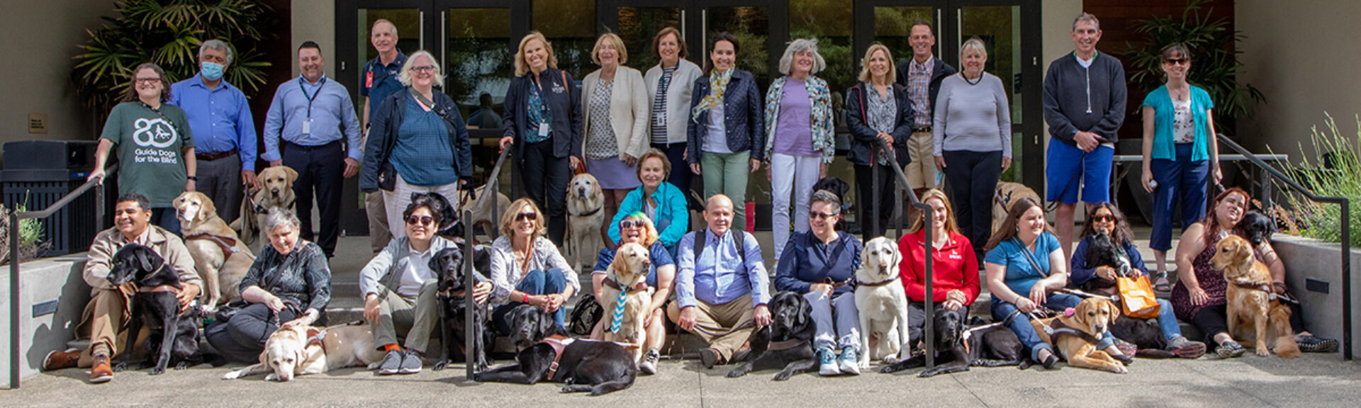 A large group of people and guide dogs pose for a group photo.