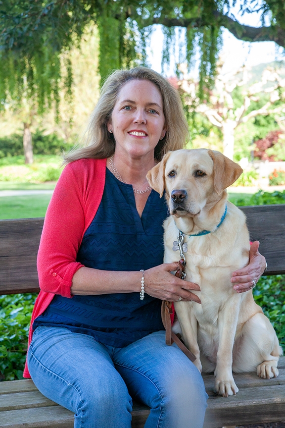 VP of Marketing and Communications Karen Woon, seated on a bench next to a yellow Lab.