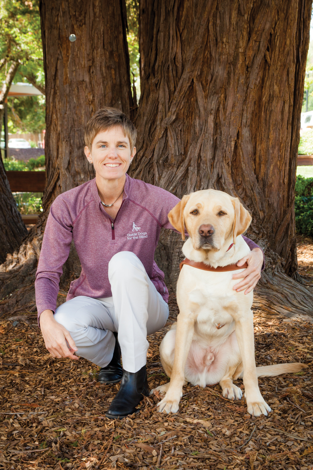 A portrait of Kristin Lucas sitting next to a yellow Lab.