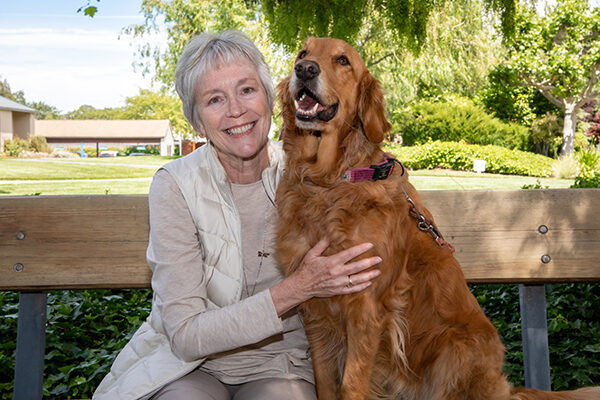 Joan Scotts sits next to a Golden Retriever