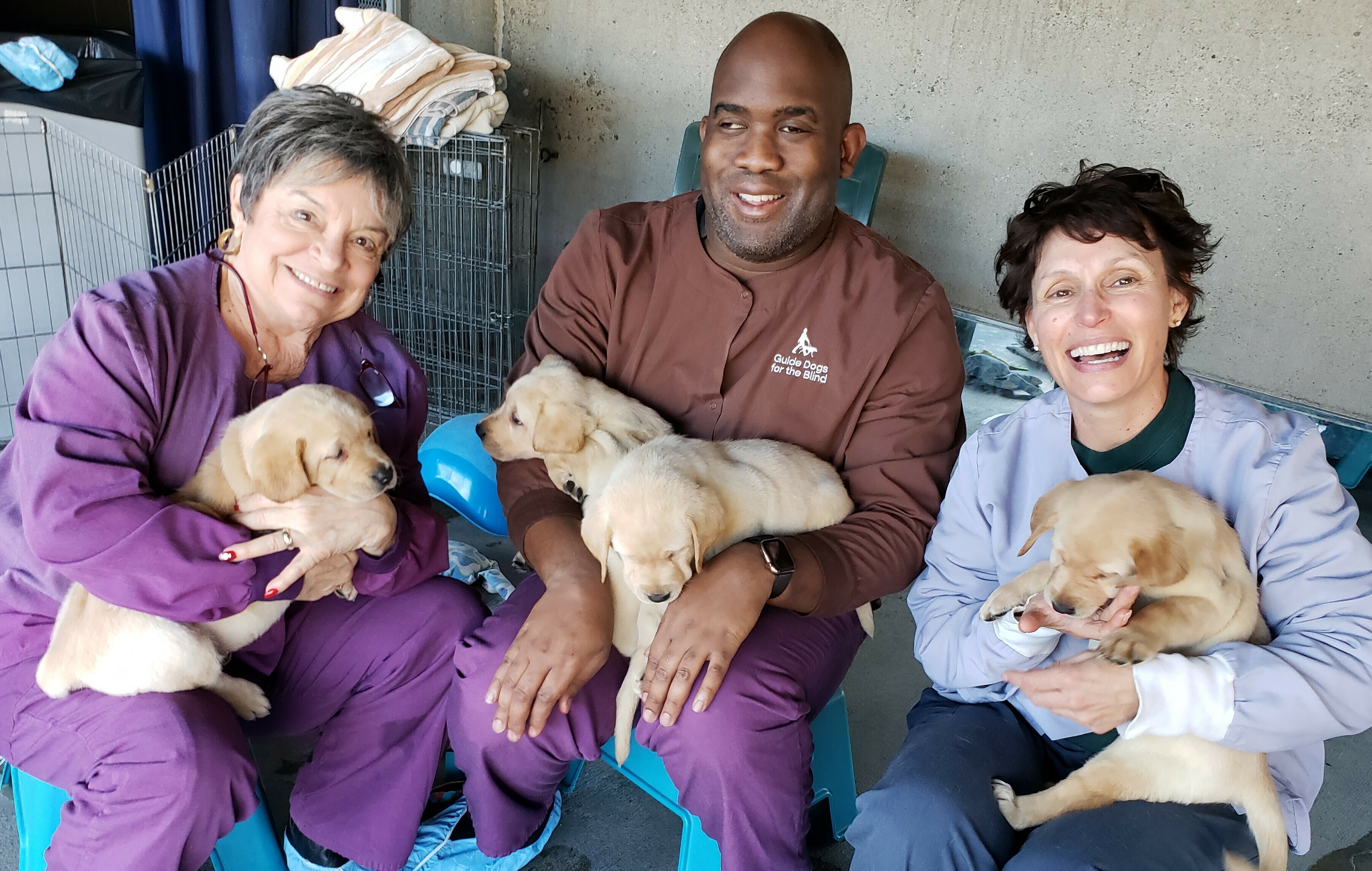 Gail and Annie Martin cuddle GDB puppies with client Abdul Kamara