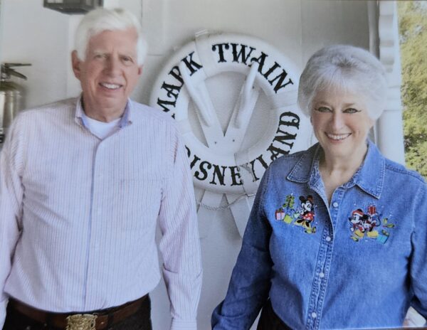A man and a woman stand smiling at the camera.