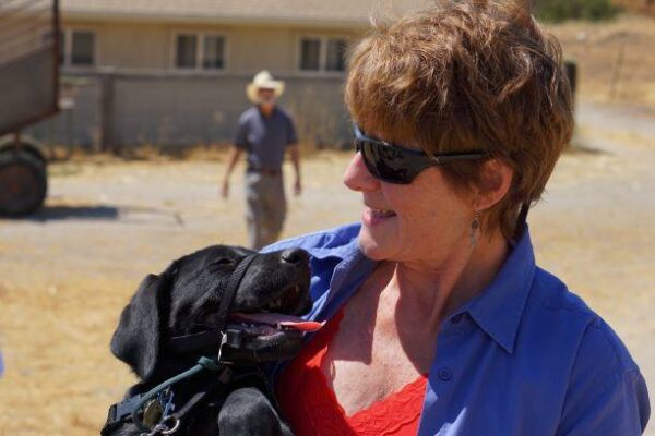 Tami gazes down at a black Lab puppy she holds