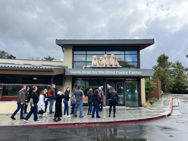 A group of people stand outside Guide Dogs for the Blind's Puppy Center.