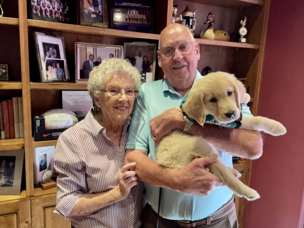 The Roxie and Jerry Enneking pose with a Golden Retriever guide dog puppy