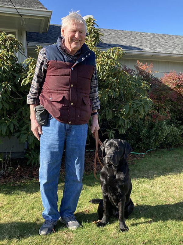 A man with a black Lab K9 Buddy dog