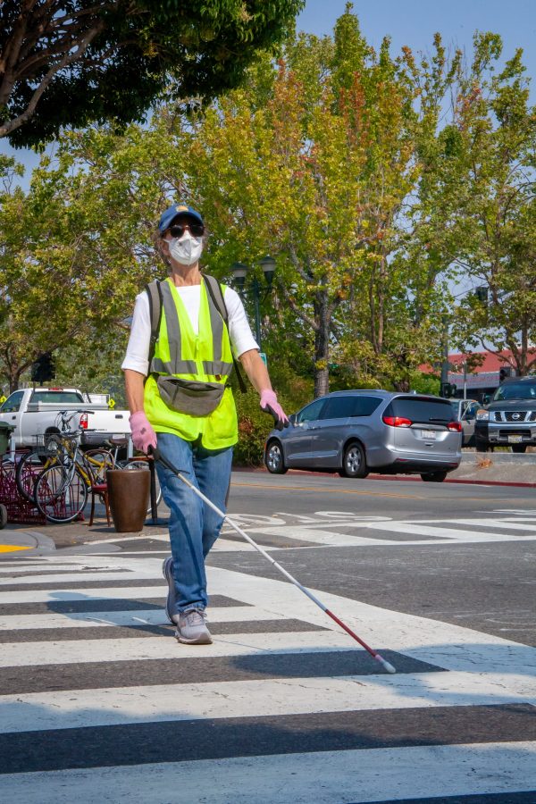 Marta Van Leuven walking with her white cane in a crosswalk.