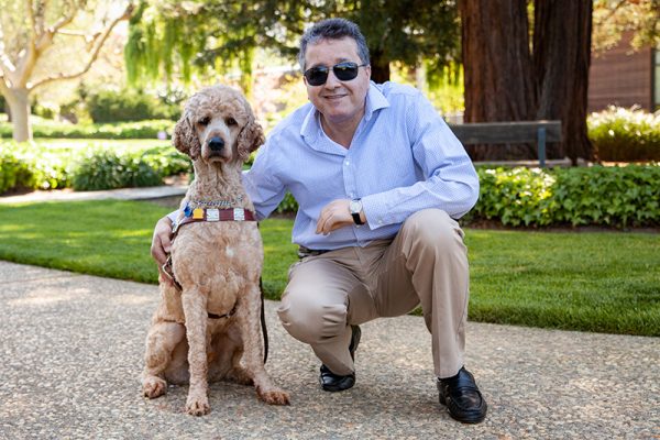 Man kneeling beside a guide dog in harness.