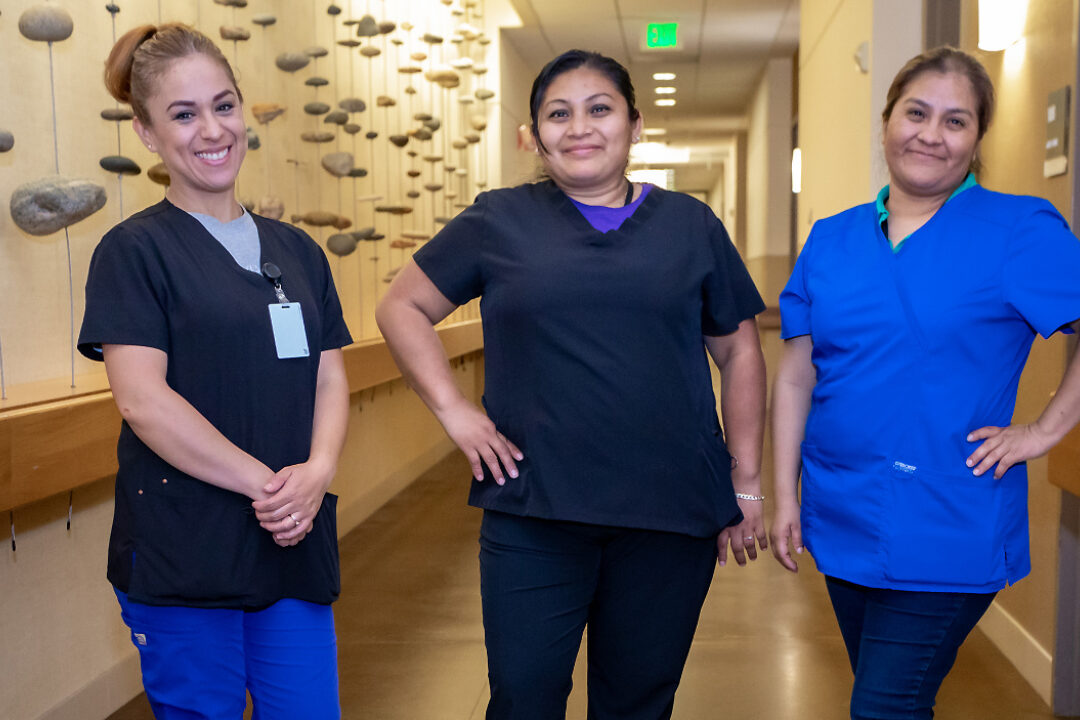 Three members of the housekeeping staff stand together in the hallway of the GDB residence building.