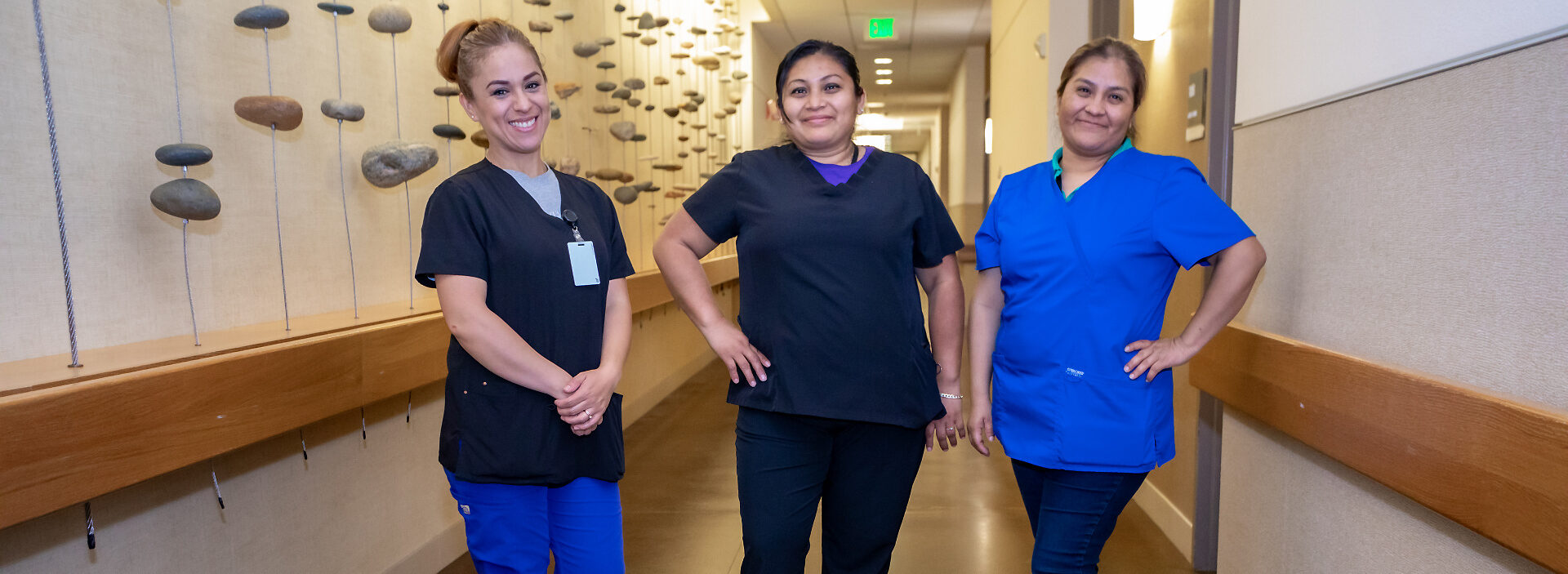 Three members of the housekeeping staff stand together in the hallway of the GDB residence building.