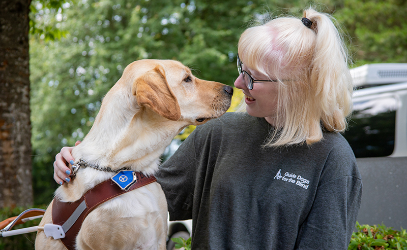A teen girl nose-to-nose with a yellow Lab guide dog.