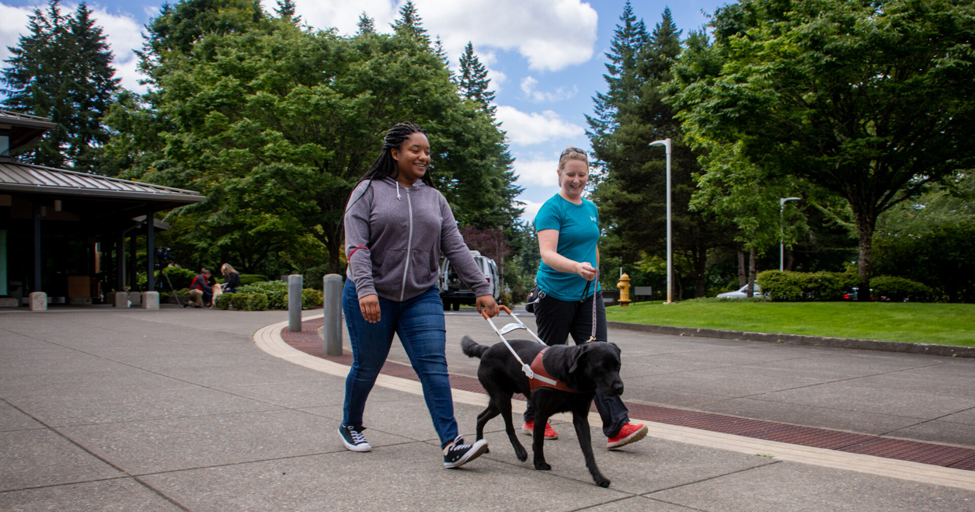 A person walks with a guide dog with the assistance of a guide dog mobility instructor.