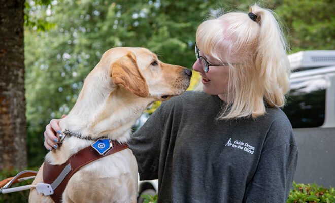 A teen girl nose-to-nose with a yellow Lab guide dog.