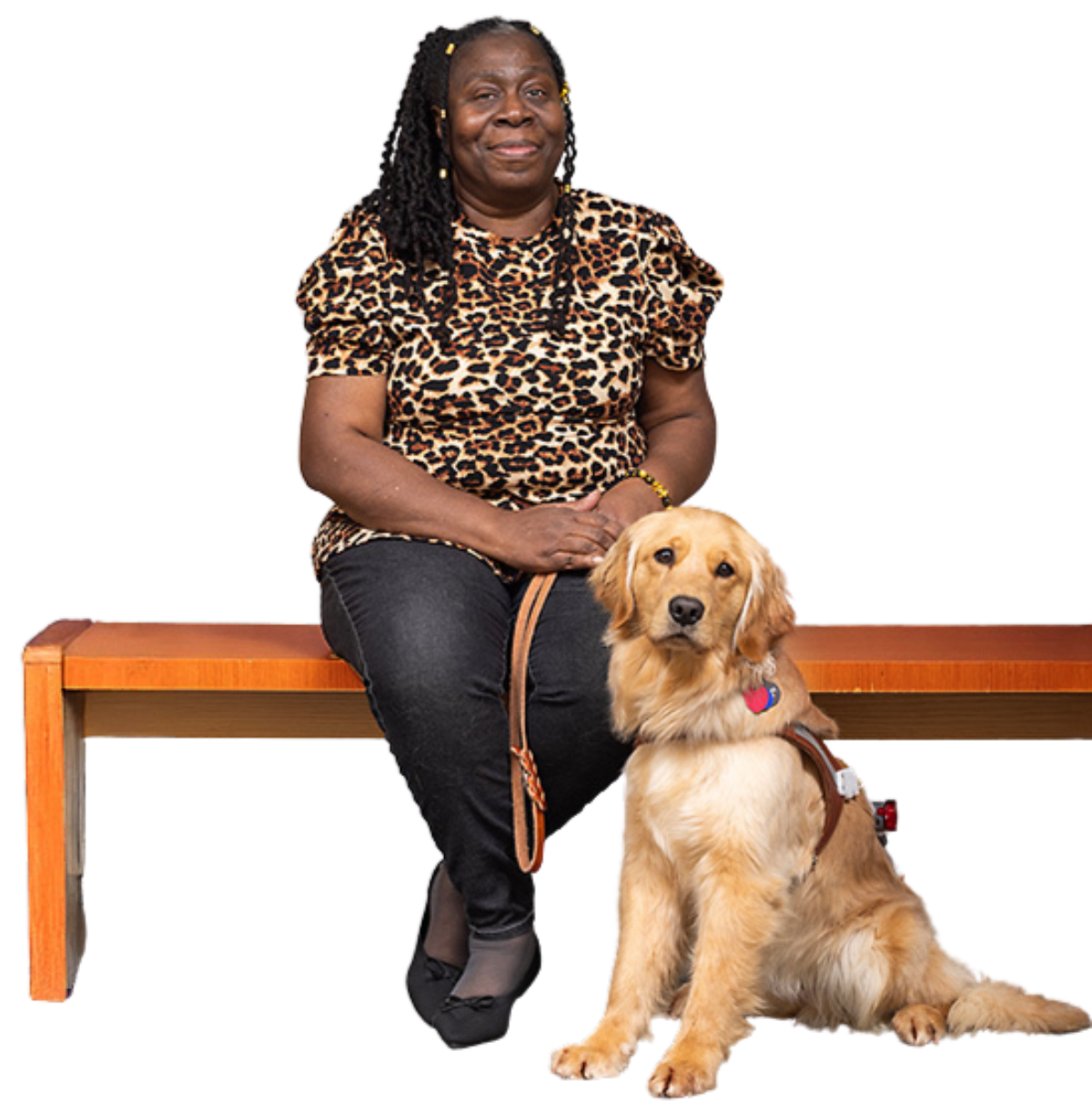 A woman is seated on a bench with her Golden Retriever guide dog seated beside her.