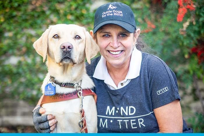 A GDB client seated beside her yellow Lab guide dog.