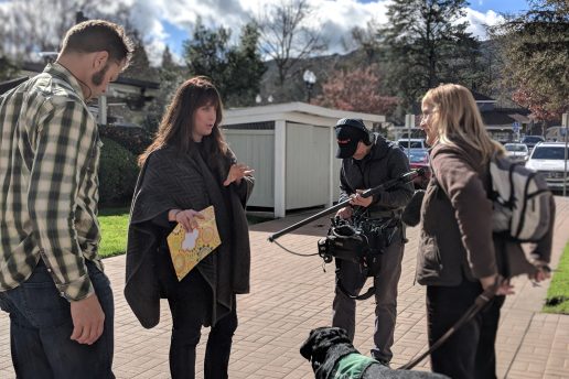 Dana works with her crew during the filming of Pick of the Litter. She gives instructions to a puppy raiser who is working with a black Lab guide dog in training.