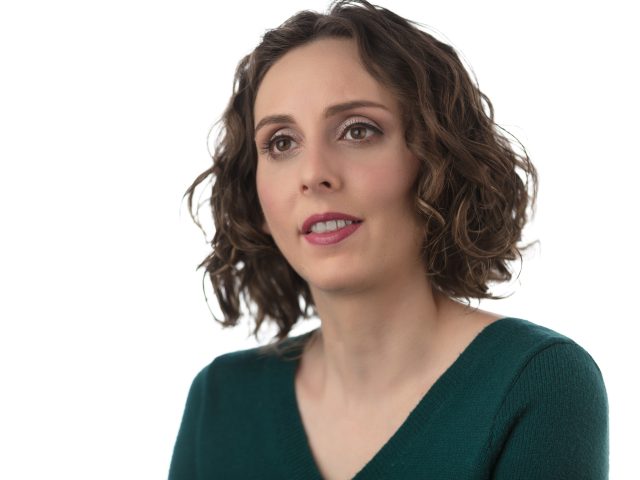 Headshot of Dr. Arielle Silverman. She has brown curly hair and is wearing a dark green top.