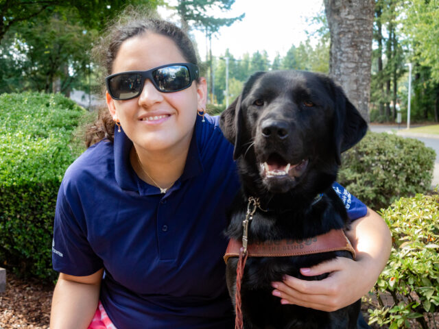Program participant embraces a black Lab guide dog.