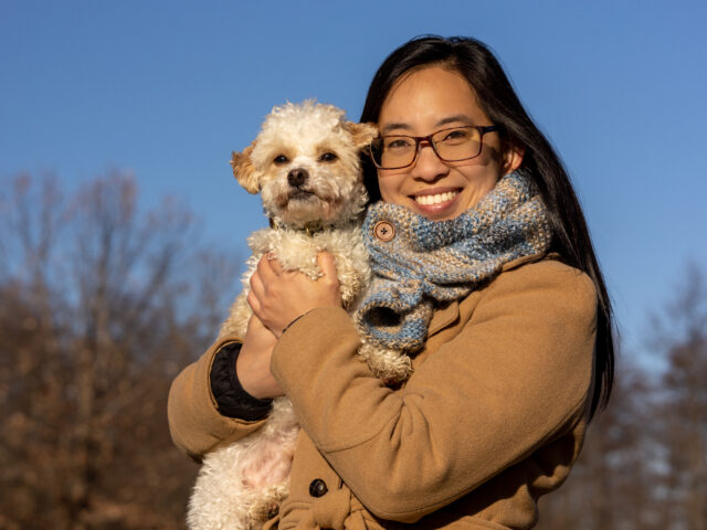 Dr. Lynna Feng holds her white dog in an embrace.