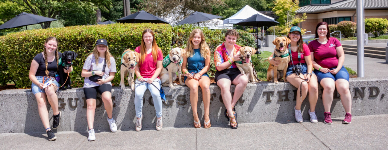 A group of people and puppies pose for a group photo.