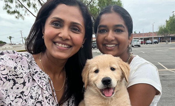 A mother and daughter puppy raising volunteers with their Golden Retriever guide dog puppy.