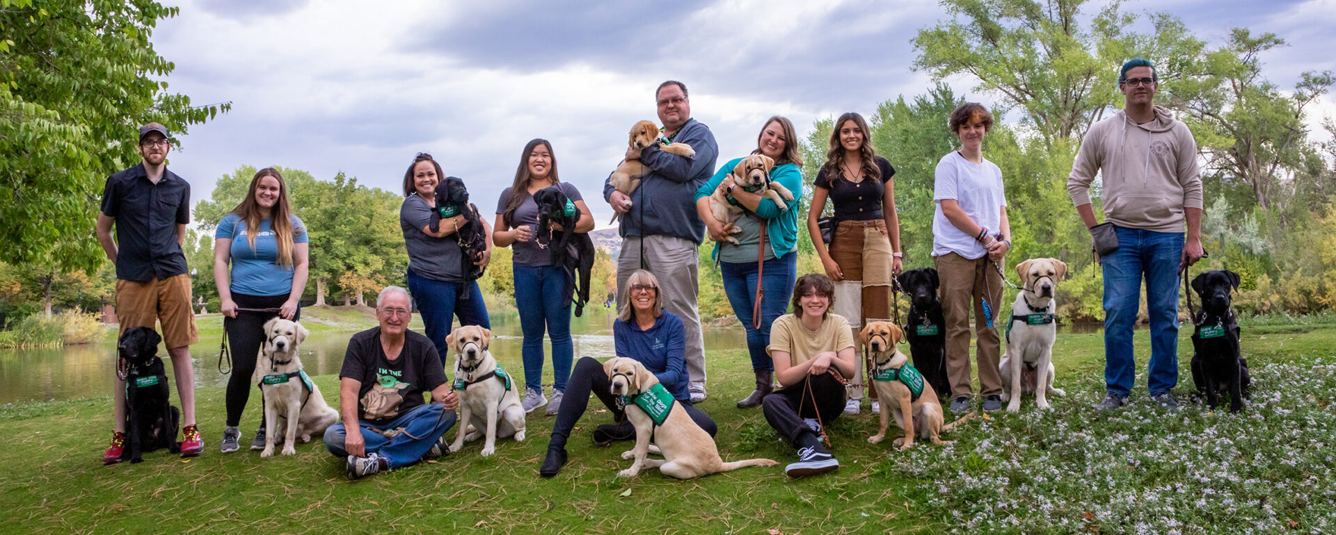 A large group of volunteer puppy raisers pose for a group photo with the puppies they are raising.