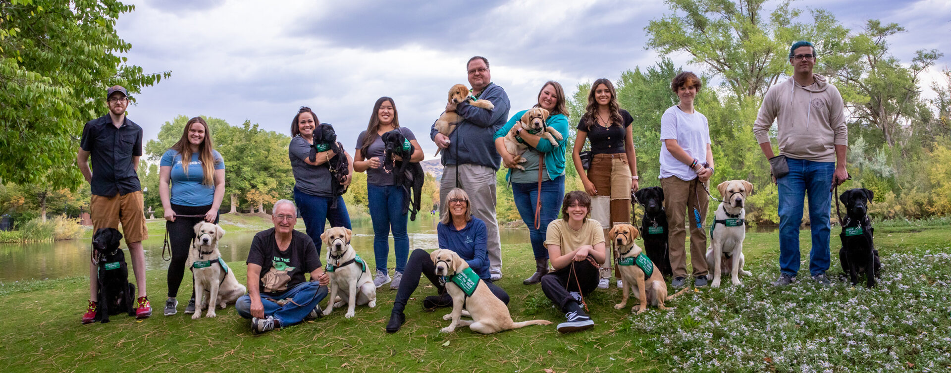 A large group of volunteer puppy raisers pose for a group photo with the puppies they are raising.