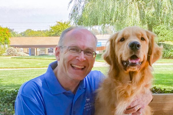 Harold Rosenblume seated next to a Golden Retriever