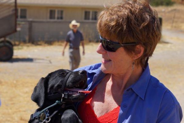 Tami gazes down at a black Lab puppy she holds