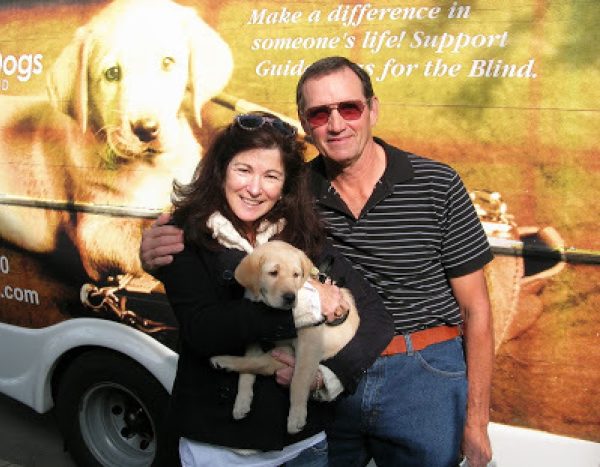 Nancy and Don Bloyer with yellow Lab guide dog puppy January in front of the GDB Puppy Truck.