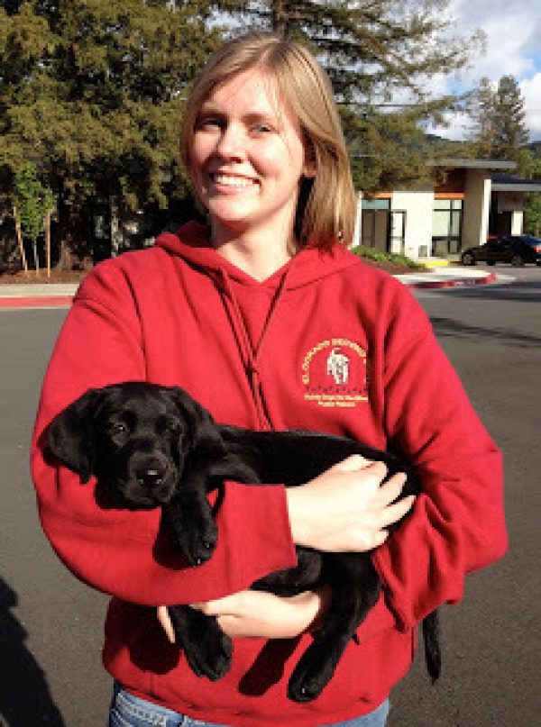 Gina holding a black Lab puppy in her arms.