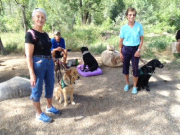 Two Southwest Brighteyes puppy raisers and their guide dog puppies pose with Trevor and Tennille (black Lab) in the wilderness.